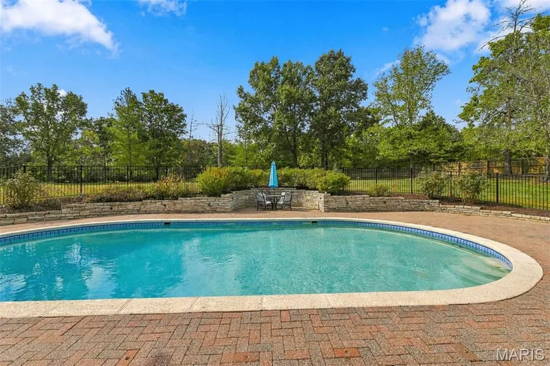 Oval swimming pool with a tile border, surrounded by a brick paver deck — 2785 Sun Meadow Drive, Wildwood, MO 63005