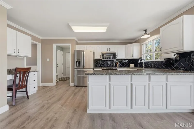 Kitchen with granite countertops, peninsula island counter seating for four, pantry, family desk, and stainless-steel appliances. Adjoins: Breakfast Area, Dining Room, and Mud Room with Laundry. — 386 Beckley Place, St Charles, MO 63304