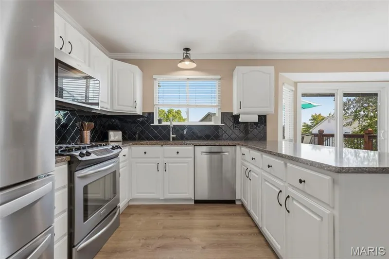Kitchen with granite countertops, peninsula island counter seating for four, pantry, family desk, and stainless-steel appliances. Adjoins: Breakfast Area, Dining Room, and Mud Room with Laundry. — 386 Beckley Place, St Charles, MO 63304