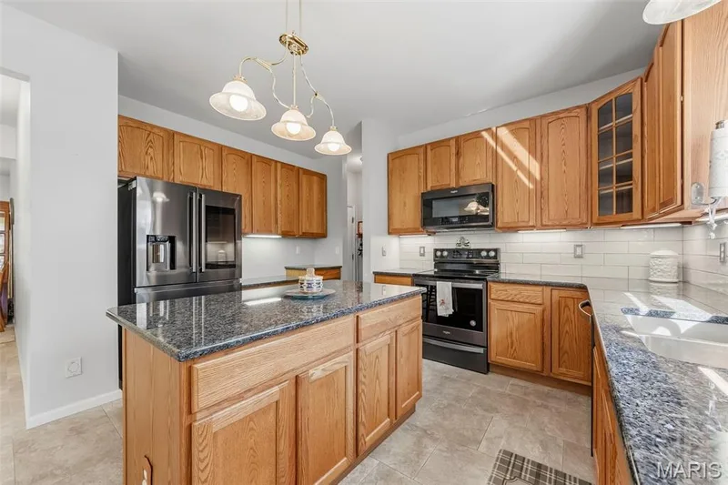 Updated kitchen featuring black stainless steel appliances, granite countertops, backsplash and under cabinet lighting! — 559 John Meyer Drive, St Charles, MO 63304
