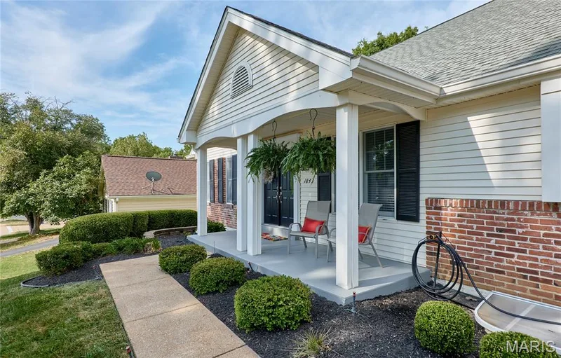 Covered porch entry featuring white columns, a brick facade, white siding, and black window shutters — 1843 Shadywood Court, Chesterfield, MO 63017