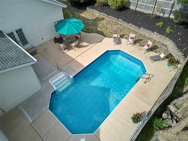 In-ground swimming pool with integrated steps, surrounded by a concrete patio, retaining walls, and a privacy fence — 1843 Shadywood Court, Chesterfield, MO 63017