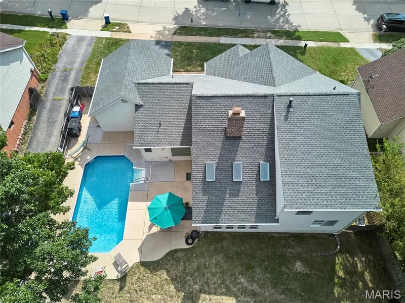 In-ground swimming pool with surrounding concrete patio, multi-pitched roofline, and brick chimney — 1843 Shadywood Court, Chesterfield, MO 63017