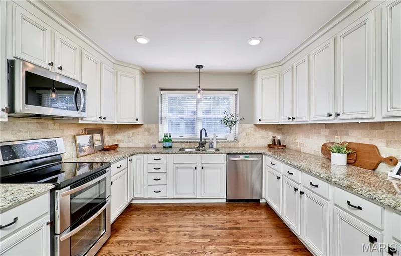 White cabinetry, stainless steel appliances, stone countertops, tile backsplash, and wood-finish flooring — 1843 Shadywood Court, Chesterfield, MO 63017