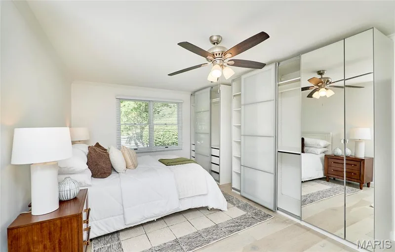 Light wood-finish flooring, built-in mirrored wardrobes, built-in frosted panel wardrobes, ceiling fan, and large window with blinds — 1843 Shadywood Court, Chesterfield, MO 63017