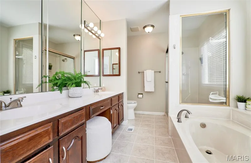 Dual vanity with wood-finish cabinetry, white countertops, and integrated sinks — 1843 Shadywood Court, Chesterfield, MO 63017