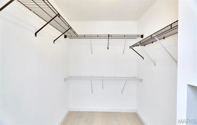 Walk-in closet with multi-level wire shelving and hanging rods, featuring wood-finish flooring — 1843 Shadywood Court, Chesterfield, MO 63017