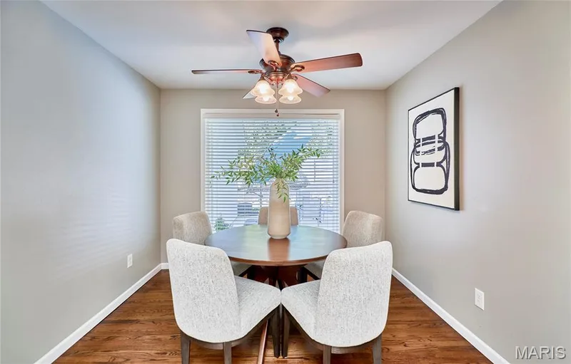 Recessed dining space featuring rich wood-finish flooring, a window with horizontal blinds, and an attached ceiling fan with lighting — 1843 Shadywood Court, Chesterfield, MO 63017