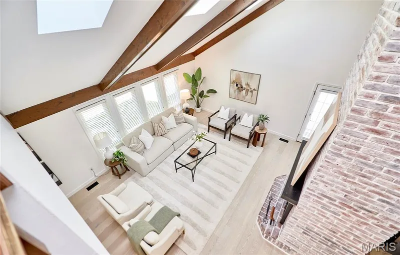 Vaulted ceiling with exposed wood beams, skylights, wood-finish flooring, brick fireplace, and multiple windows — 1843 Shadywood Court, Chesterfield, MO 63017