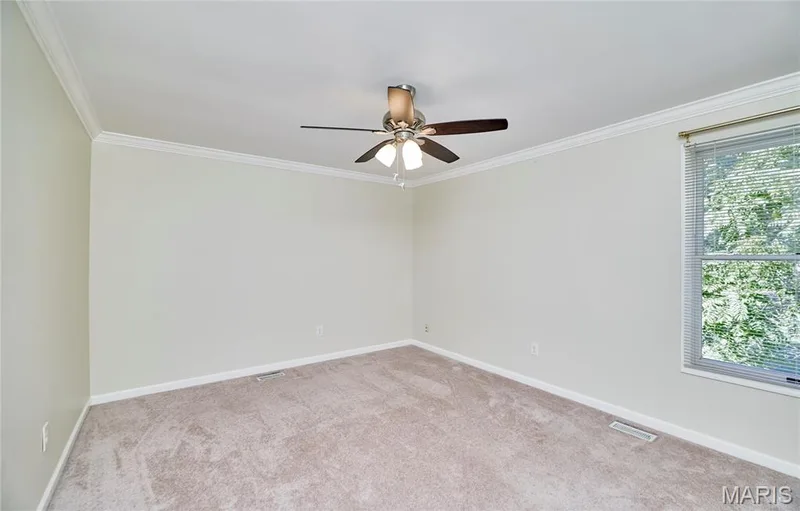 Neutral wall color, crown molding, ceiling fan, carpet flooring, and a window with blinds — 1843 Shadywood Court, Chesterfield, MO 63017