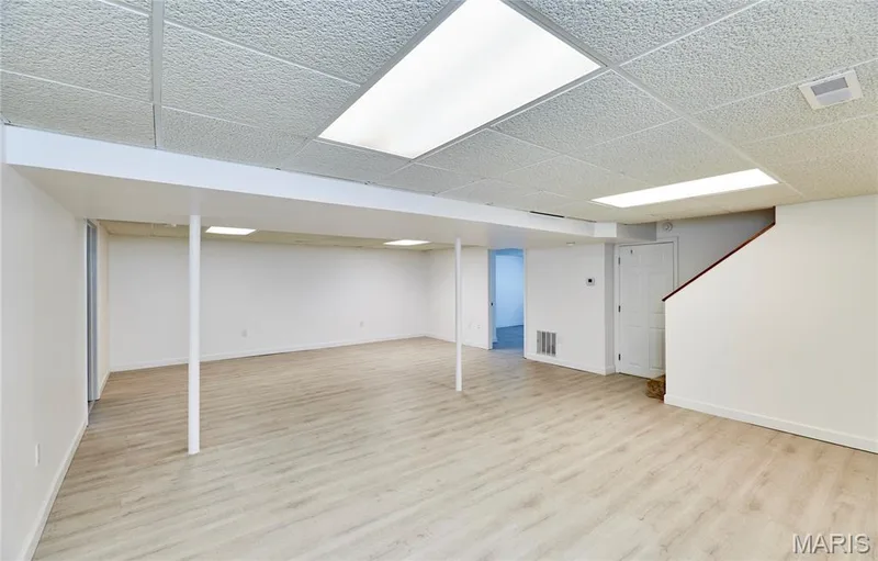 Expansive lower-level space featuring wood-finish flooring, white walls, and a drop ceiling with integrated lighting — 1843 Shadywood Court, Chesterfield, MO 63017