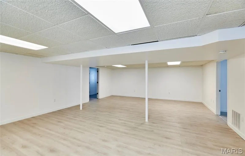 Expansive room featuring wood-finish flooring, drop ceiling with integrated lighting, and white walls — 1843 Shadywood Court, Chesterfield, MO 63017