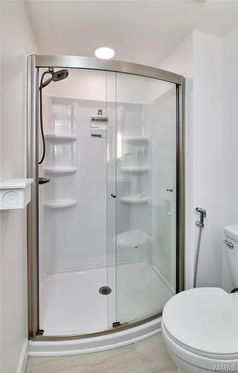 Curved glass shower enclosure with brushed nickel frame, integrated shelving, and a bronze-finish shower head — 1843 Shadywood Court, Chesterfield, MO 63017