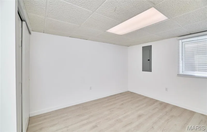 Lower level bedroom with egress with light wood-finish flooring with white walls, a grid-patterned ceiling, and a flush-mounted rectangular light fixture — 1843 Shadywood Court, Chesterfield, MO 63017