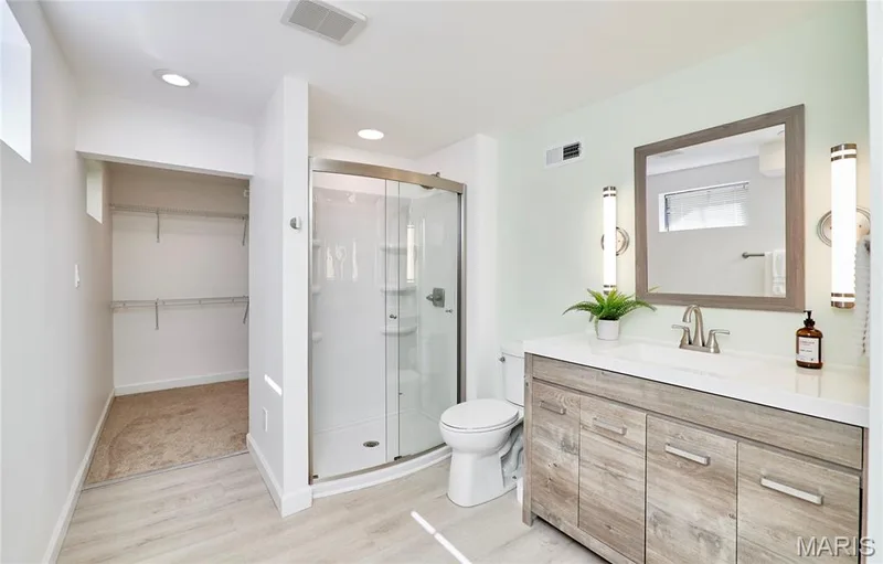 Contemporary vanity with integrated sink, wood-finish cabinetry, and brushed nickel fixtures — 1843 Shadywood Court, Chesterfield, MO 63017