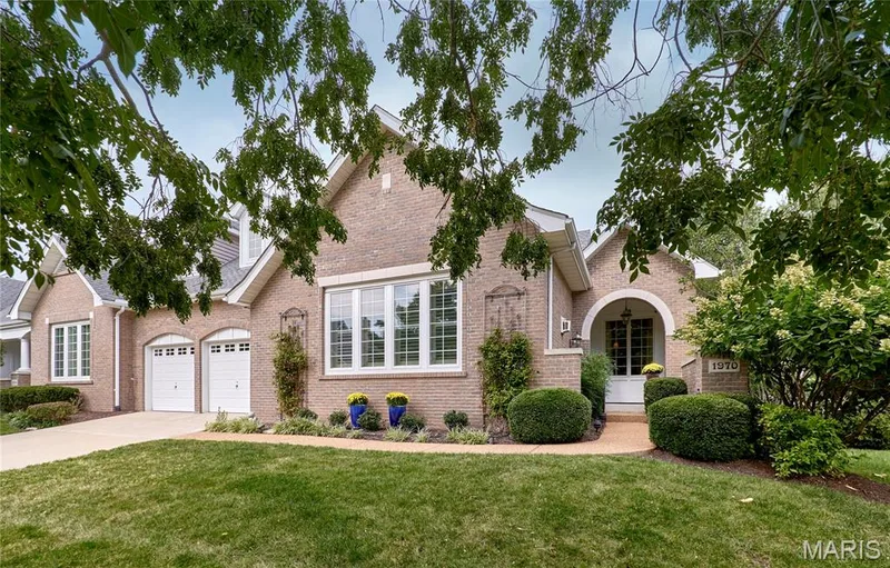 Brick facade with white trim, two-car garage with white doors, arched portico entrance, and manicured landscaping — 1970 Chesterfield Ridge Circle, Chesterfield, MO 63017