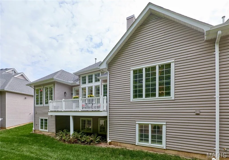 Exterior featuring horizontal siding, multiple windows with white trim, a raised deck with white railings, and a sloped grass lawn — 1970 Chesterfield Ridge Circle, Chesterfield, MO 63017