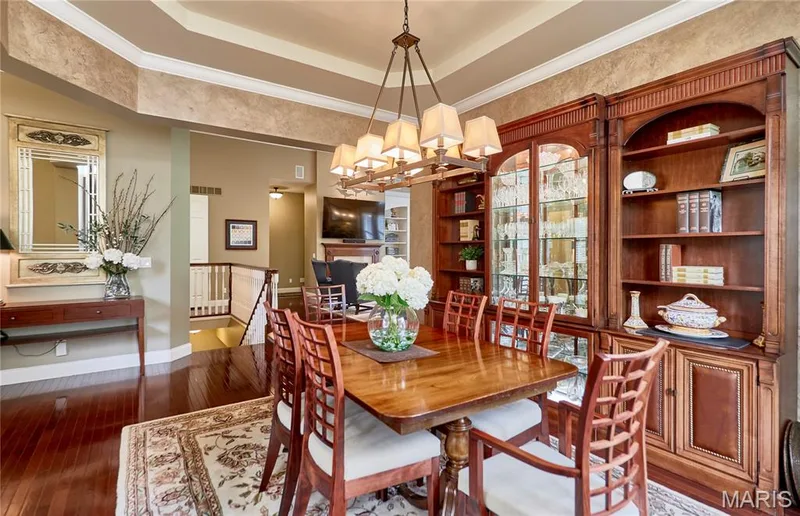 Rich wood-finish flooring, built-in display cabinetry, tray ceiling, and a multi-light chandelier — 1970 Chesterfield Ridge Circle, Chesterfield, MO 63017