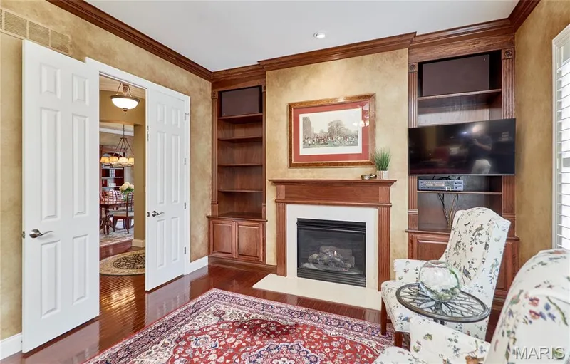 Wood-finish flooring, built-in shelving, fireplace with mantel, crown molding, and plantation shutters — 1970 Chesterfield Ridge Circle, Chesterfield, MO 63017