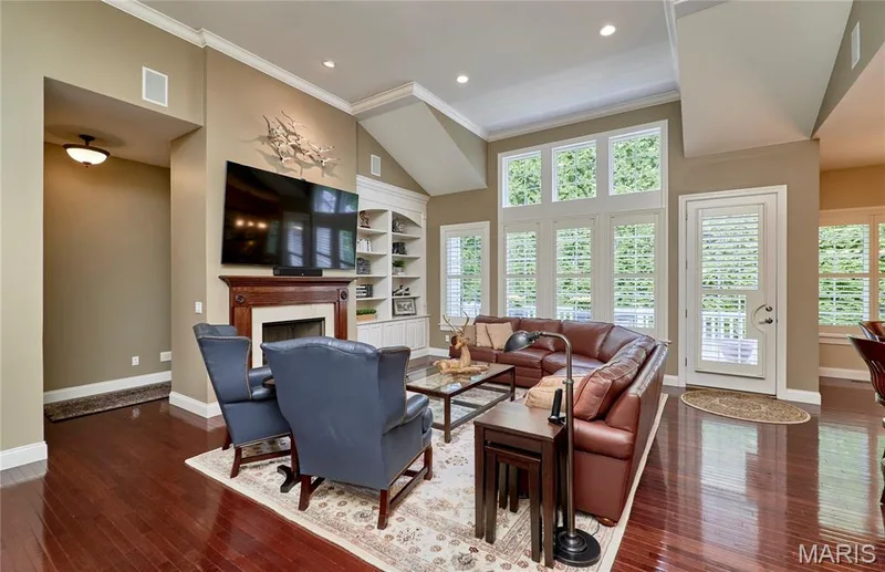 Varnished wood-finish flooring throughout, featuring a fireplace with a wood mantle, built-in shelving, and a vaulted ceiling — 1970 Chesterfield Ridge Circle, Chesterfield, MO 63017