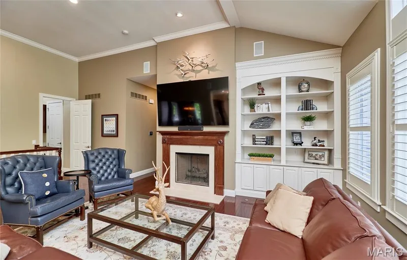 Hardwood flooring, fireplace with wood mantel, built-in shelving, crown molding, and window shutters — 1970 Chesterfield Ridge Circle, Chesterfield, MO 63017