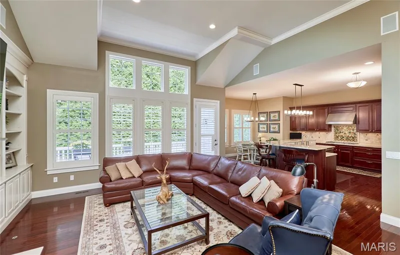Hardwood flooring, vaulted ceiling, built-in shelving, white plantation shutters, and a kitchen featuring dark wood cabinetry — 1970 Chesterfield Ridge Circle, Chesterfield, MO 63017