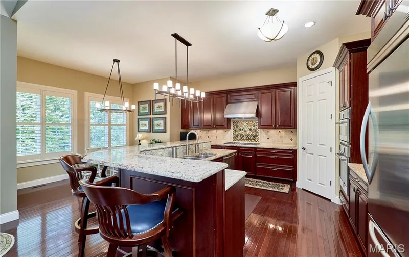 Gourmet kitchen featuring rich cabinetry, marble-topped island with seating, built-in refrigerator, and pendant lighting — 1970 Chesterfield Ridge Circle, Chesterfield, MO 63017