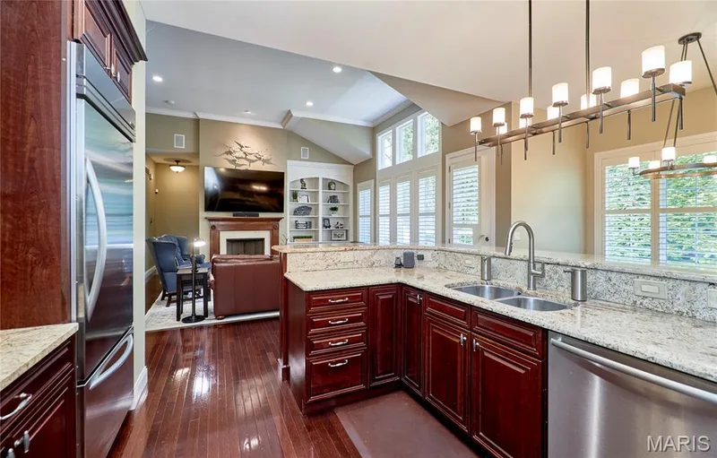 Gourmet kitchen featuring rich cabinetry with multiple drawers and storage, stainless steel appliances, light stone countertops, and a large center island with seating — 1970 Chesterfield Ridge Circle, Chesterfield, MO 63017