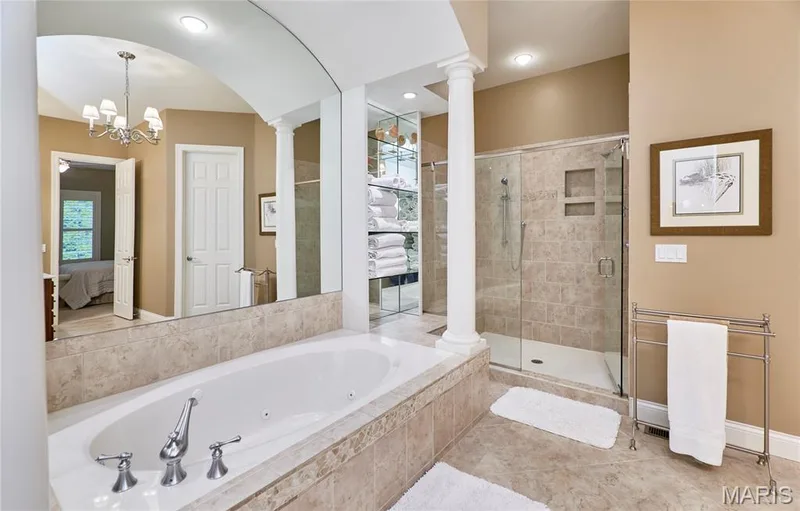 Soaking tub with chrome fixtures, glass-enclosed shower with tiled walls and built-in niches, and a full-width wall mirror — 1970 Chesterfield Ridge Circle, Chesterfield, MO 63017