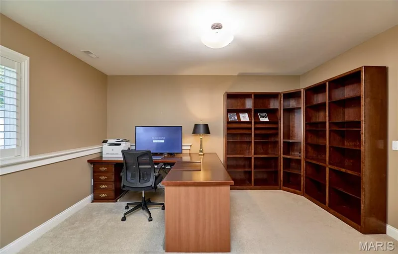 Built-in corner shelving, neutral carpet, ceiling-mounted light fixture, window with plantation shutters, and a rich wood-finish desk — 1970 Chesterfield Ridge Circle, Chesterfield, MO 63017