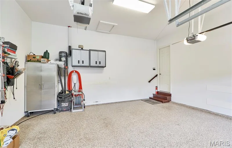 Attached garage featuring a light-toned speckled floor coating, white walls, and built-in wall cabinets — 1970 Chesterfield Ridge Circle, Chesterfield, MO 63017