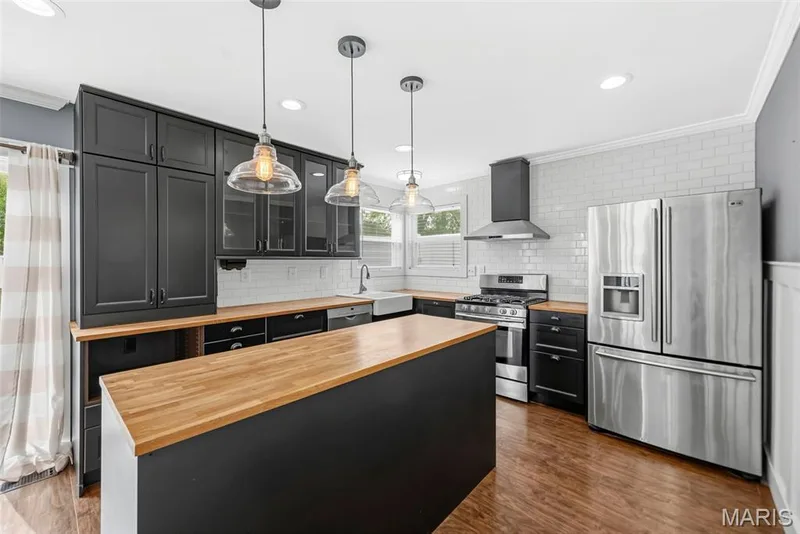Kitchen featuring dark cabinetry, butcher block countertops, stainless steel appliances, a subway tile backsplash — 242 Ashford Oaks Drive, Wentzville, MO 63385