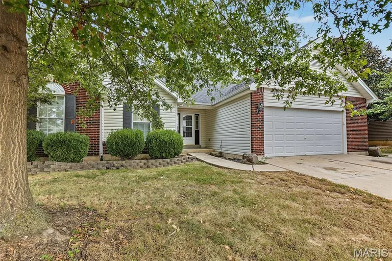Brick and siding exterior with an attached garage, arched window, and established landscaping — 521 Sceptre Road, Wentzville, MO 63385
