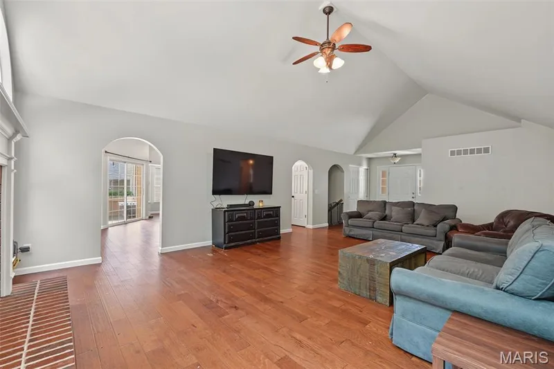 Vaulted ceiling with a ceiling fan, wood-finish flooring, brick hearth, and arched doorways — 521 Sceptre Road, Wentzville, MO 63385