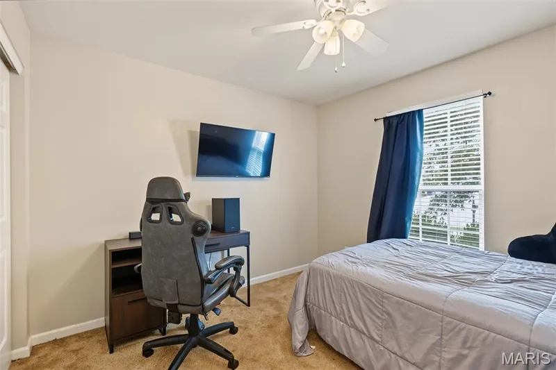 Neutral-toned walls with ceiling fan light fixture, light brown carpet, and a window with white blinds — 521 Sceptre Road, Wentzville, MO 63385