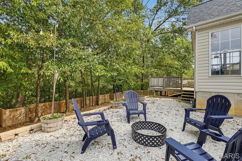 Gravel patio area featuring a fire pit, string lighting, and a wood privacy fence — 521 Sceptre Road, Wentzville, MO 63385