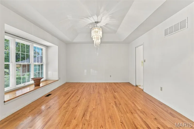Hardwood flooring, tray ceiling with a multi-tiered chandelier, a wide bay window — 14033 Baywood Villages Drive, Chesterfield, MO 63017