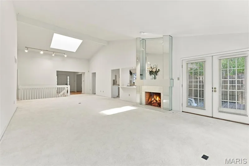 Vaulted ceiling with skylight, white brick fireplace, mirrored accents, and French doors — 14033 Baywood Villages Drive, Chesterfield, MO 63017
