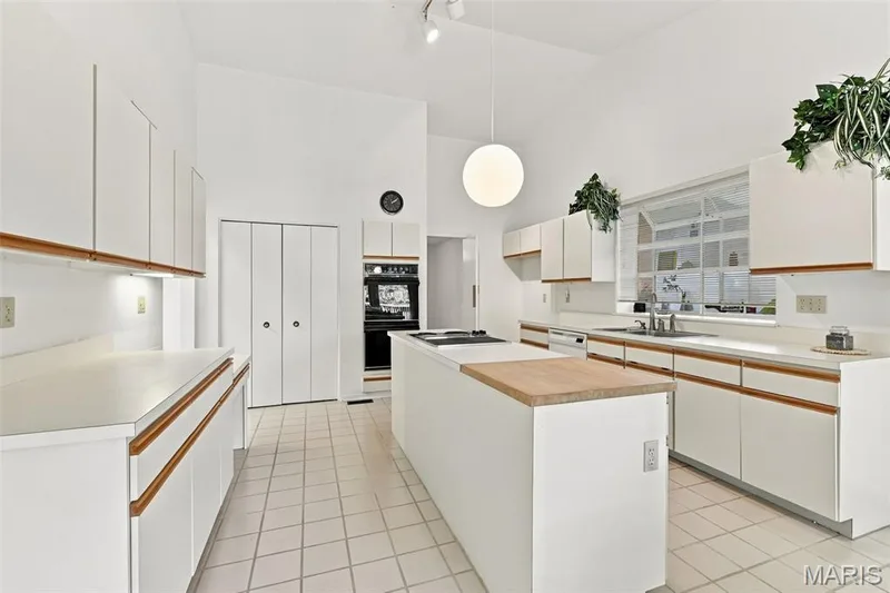 Vaulted ceilings, white cabinetry with wood-finish accents, center island, built-in double oven — 14033 Baywood Villages Drive, Chesterfield, MO 63017