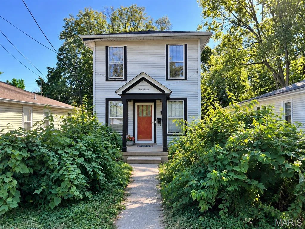 Two-story residence featuring horizontal siding, a covered front entryway with structural pillars, and a concrete walkway — 411 Adams Street, St Charles, MO 63301