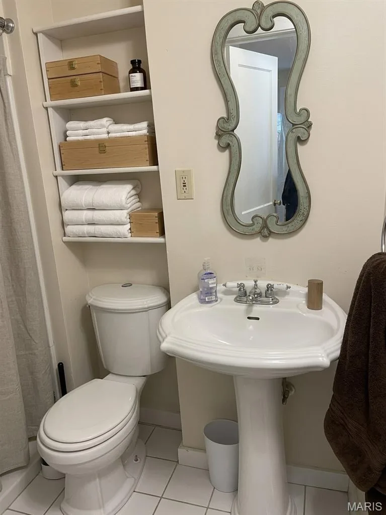 Bathroom featuring a white porcelain pedestal sink, built-in open wall shelving, and tile flooring — 411 Adams Street, St Charles, MO 63301