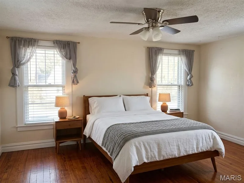 Room with wood-finish flooring, two double-hung windows, and a ceiling-mounted light fixture with fan — 411 Adams Street, St Charles, MO 63301