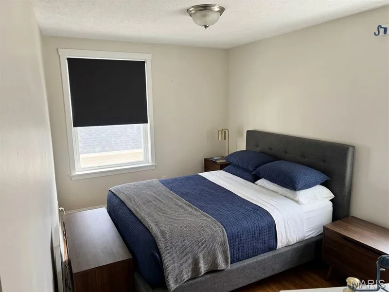 Neutral-toned interior space featuring wood-finish flooring, a single-pane window with white casing, and a flush-mount ceiling light fixture — 411 Adams Street, St Charles, MO 63301