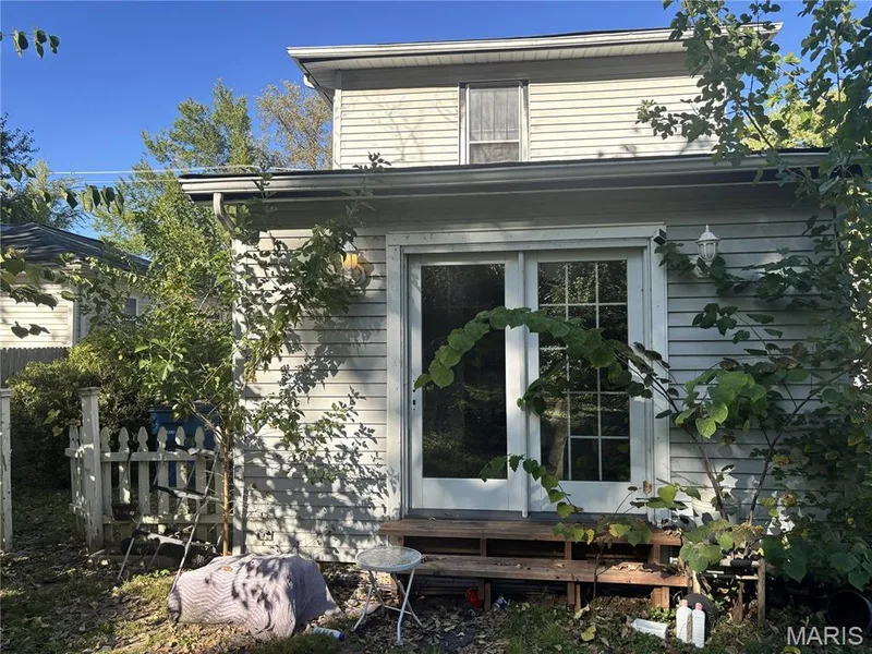 Exterior featuring horizontal siding, glass-paneled double doors, and a wood-plank deck — 411 Adams Street, St Charles, MO 63301