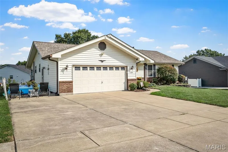 White siding exterior with brick accents, attached garage with panel door, concrete driveway, and established front landscaping — 355 Birmingham Drive, O'Fallon, MO 63366