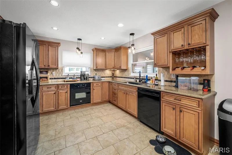 Kitchen featuring wood cabinetry, tiled flooring, built-in wine rack, and a tile backsplash — 355 Birmingham Drive, O'Fallon, MO 63366