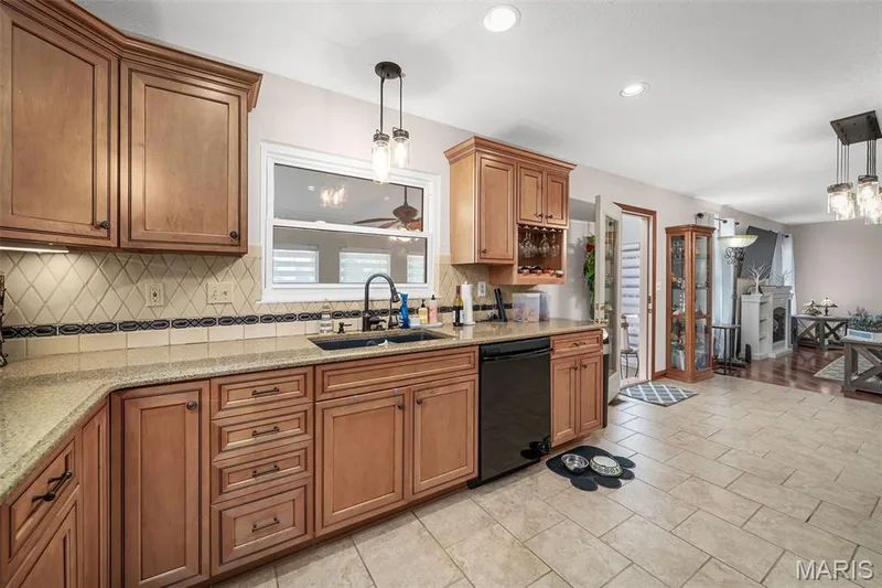 Kitchen featuring wood cabinetry, light-toned countertops, a tile backsplash, and recessed lighting — 355 Birmingham Drive, O'Fallon, MO 63366