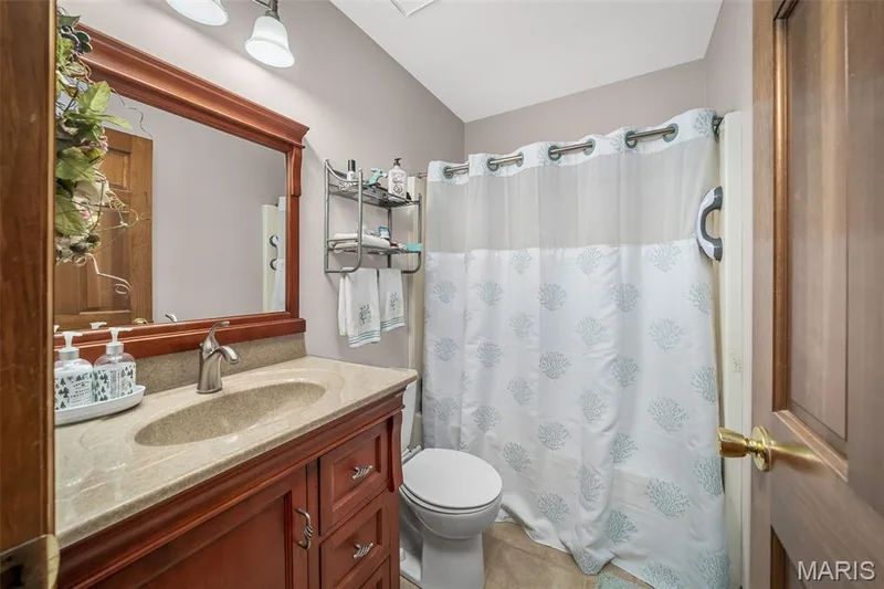 Built-in wooden vanity with a stone countertop and integrated sink — 355 Birmingham Drive, O'Fallon, MO 63366