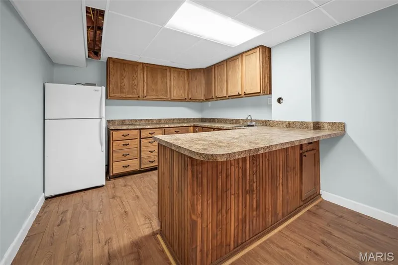Wood-finish flooring with a built-in bar, extensive cabinetry, and a drop-ceiling — 355 Birmingham Drive, O'Fallon, MO 63366