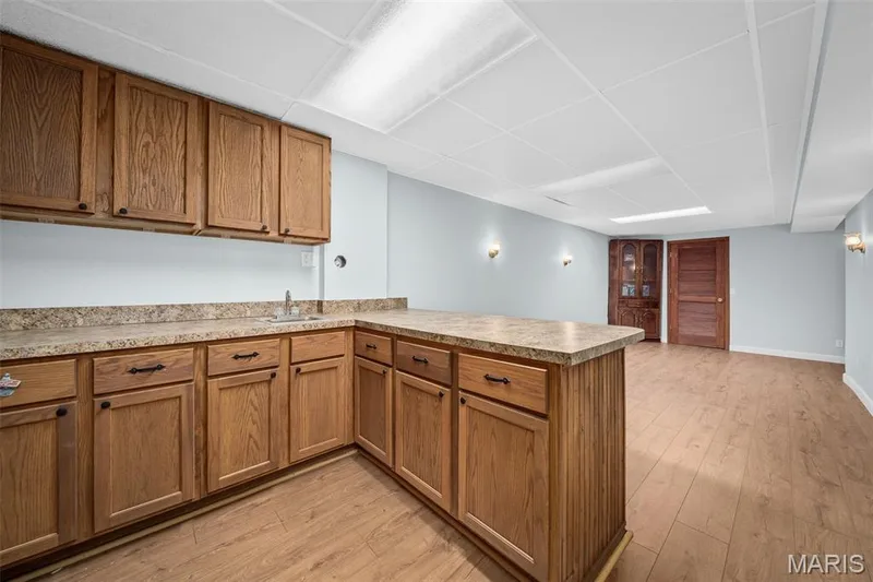 Extensive wood-finish cabinetry with dark hardware, a built-in sink, and laminate countertops — 355 Birmingham Drive, O'Fallon, MO 63366